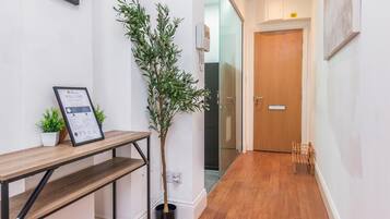 A hallway with a reception desk, a framed welcome sign, a potted plant, and a wooden door.