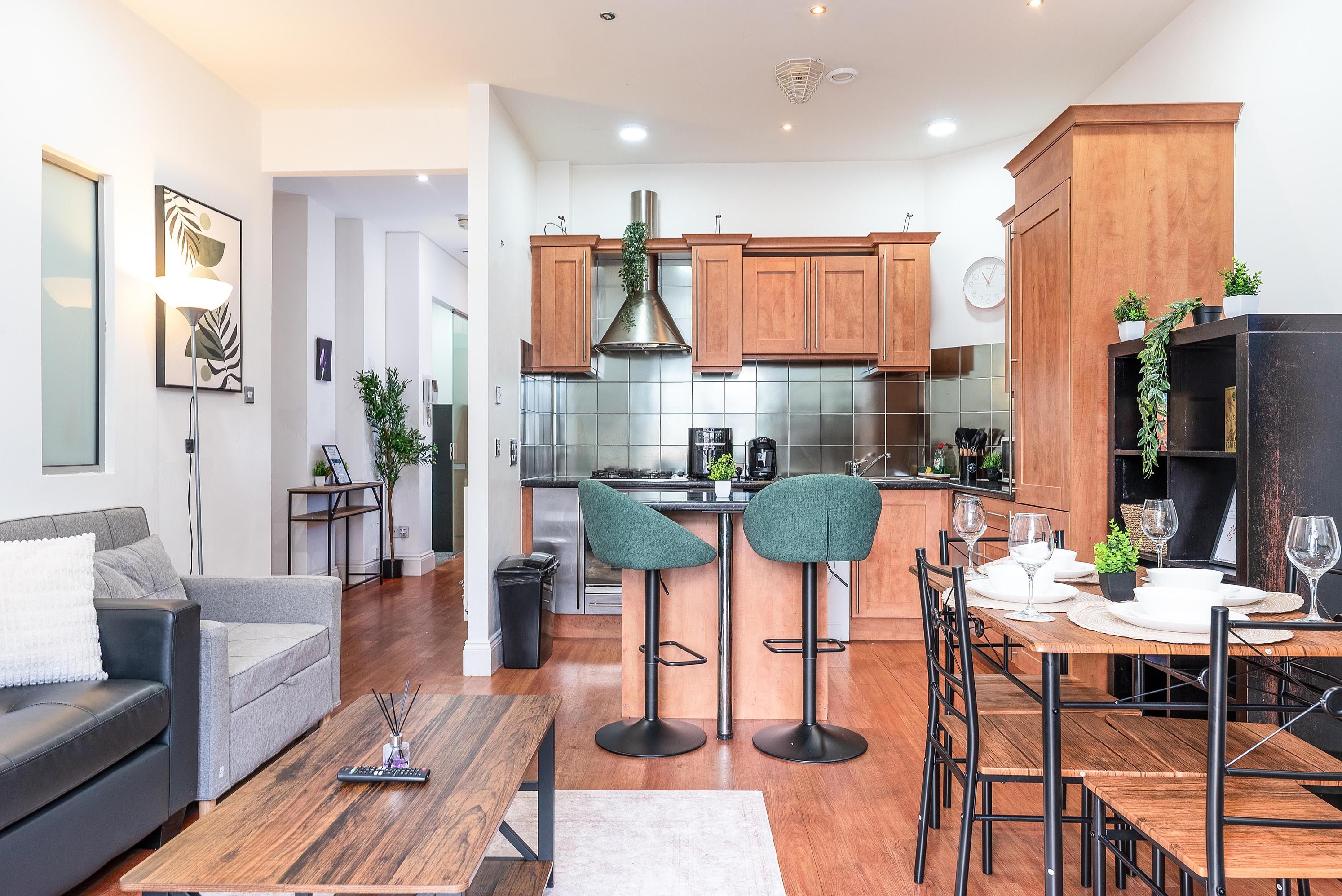 A modern kitchen with wooden cabinets, a stainless steel range hood, and a dining area with bar stools.