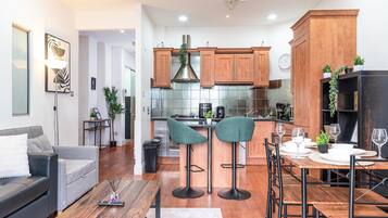 A modern kitchen with wooden cabinets, a stainless steel range hood, and a dining area with bar stools.