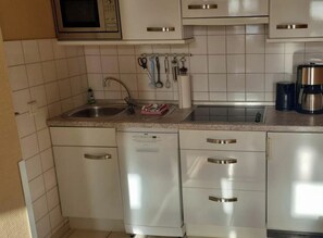 A kitchen with white cabinets, a dishwasher, a microwave, and a coffee maker. - Villa Seegatt 08 (Norderney)