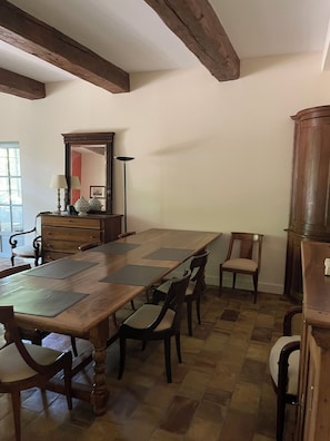 Un comedor con una larga mesa de madera, varias sillas, un aparador y una lámpara de pie.