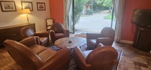 Huone, jossa on nahkaverhoillut tuolit, pieni pöytä, televisio ja näkymä ulos.