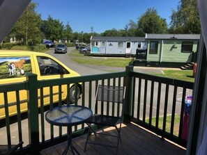 Ein Balkon mit Tisch und Stühlen, Blick auf eine Straße mit parkenden Autos und Wohnmobilen im Hintergrund.