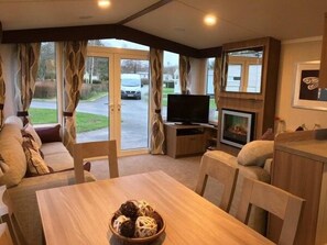 Ein gemütlicher Wohnbereich mit einer Couch, einem Tisch mit einer Schüssel voller Snacks, einem Fernseher und einem Kamin.