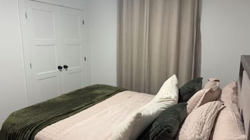 A bedroom with a bed, a door, and a curtain.