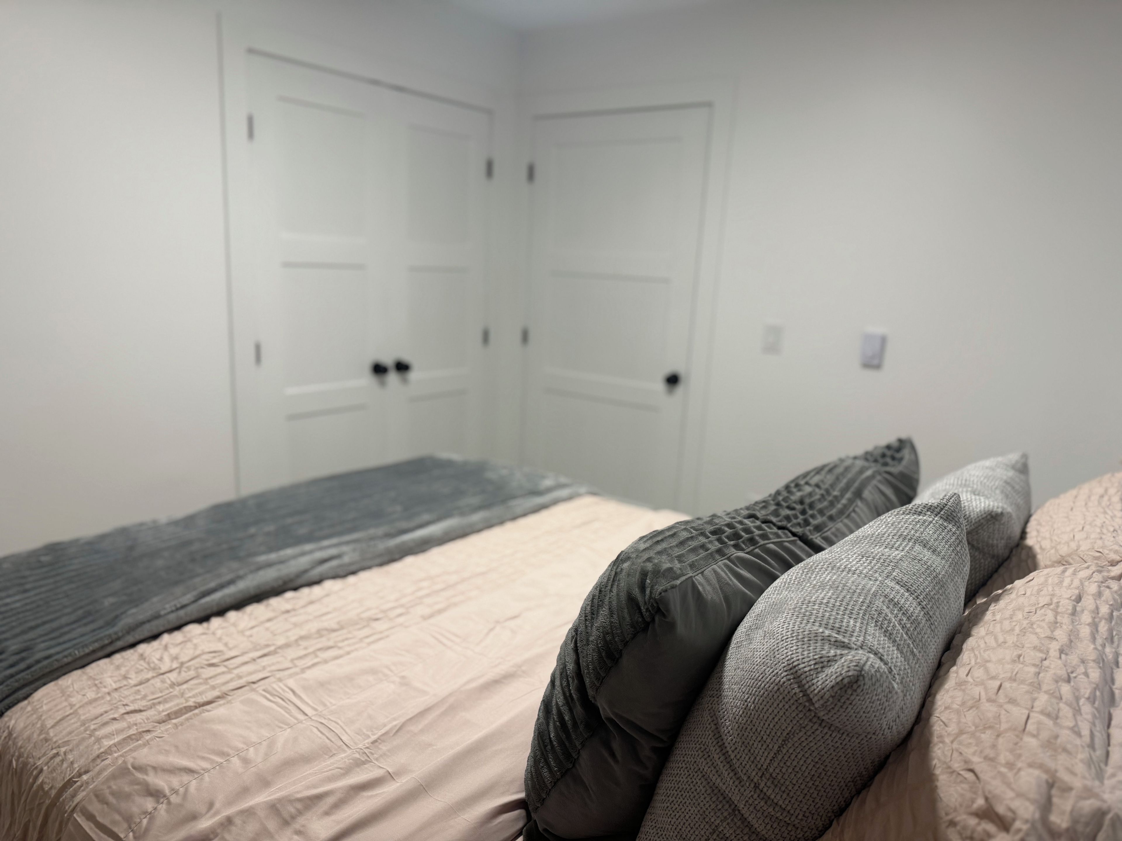 A bedroom with a bed, two doors, and a bedside table.