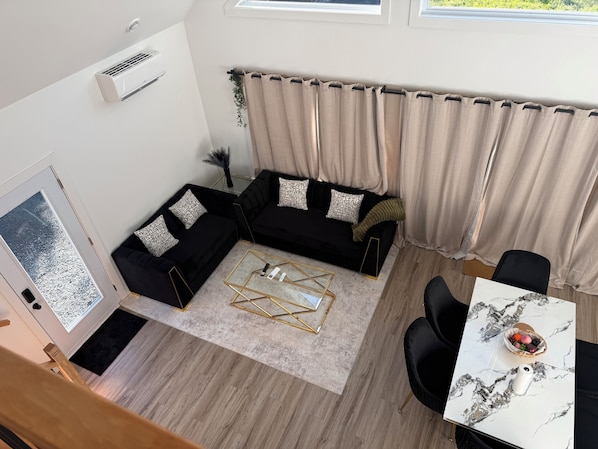 A modern living room with a sectional sofa, a coffee table, and a dining area with a table and chairs.