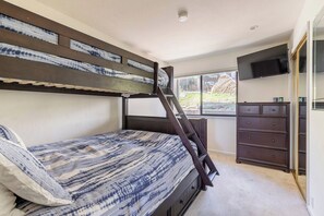 A bunk bed with a ladder, a dresser, and a TV mounted on the wall. - Stunning View Condo: Ski-in, Hot Tub (Mammoth Lakes)