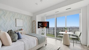Un dormitorio moderno con una cama grande, un televisor y un balcón con vistas a la ciudad.