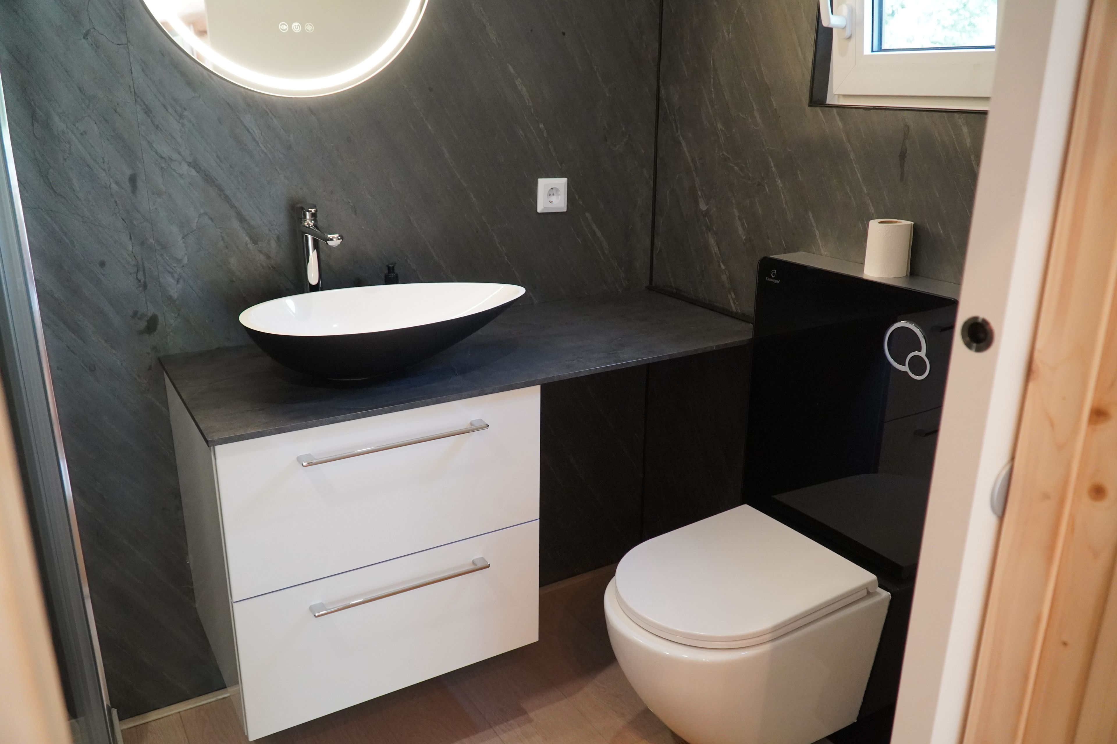 Ein Badezimmer mit einem schwarzen Waschbecken, einem weißen Schrank und einer weißen Toilette.