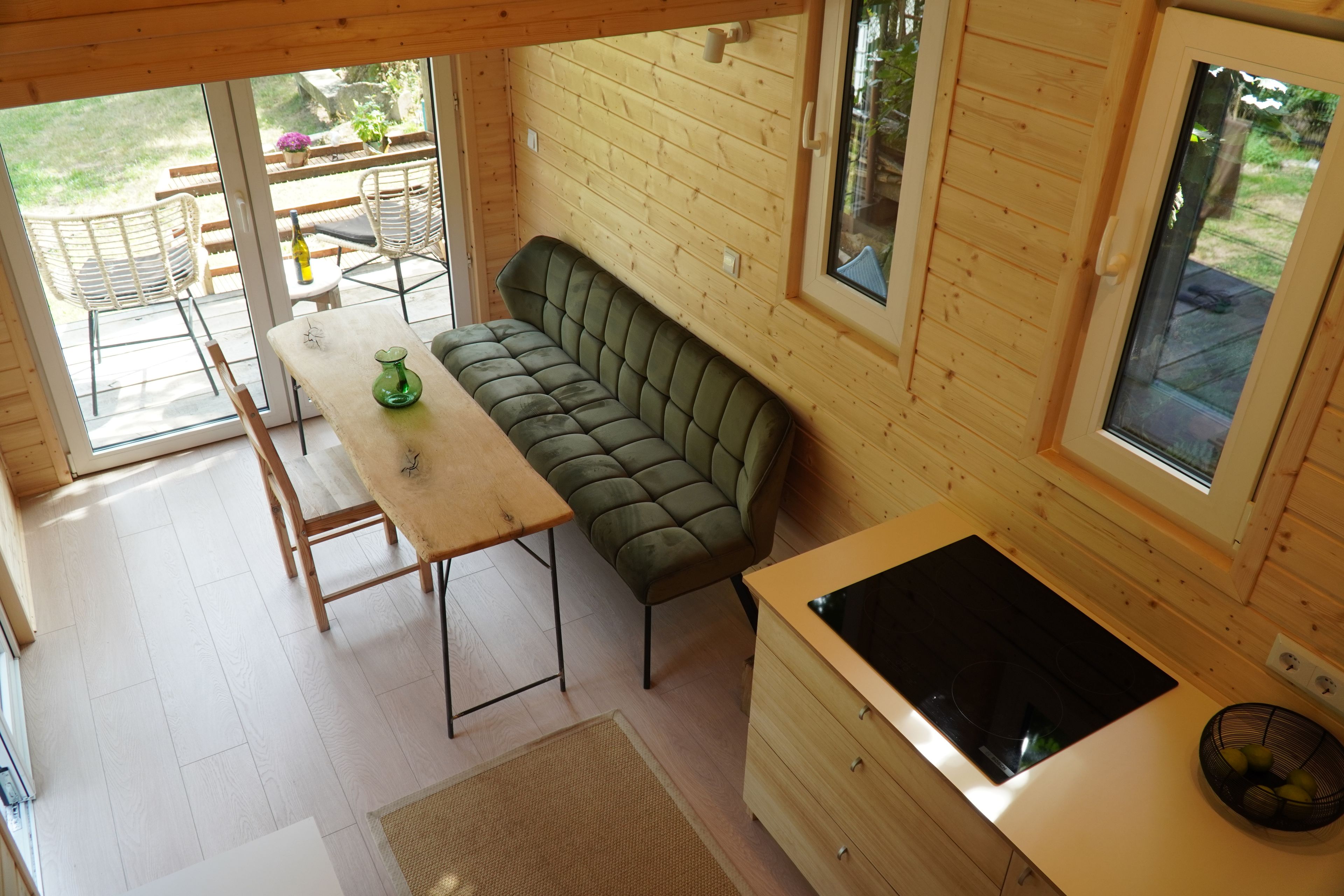 Ein gemütliches Blockhäuschen-Interieur mit einer Couch, einem Esstisch und einer Küchenzeile.
