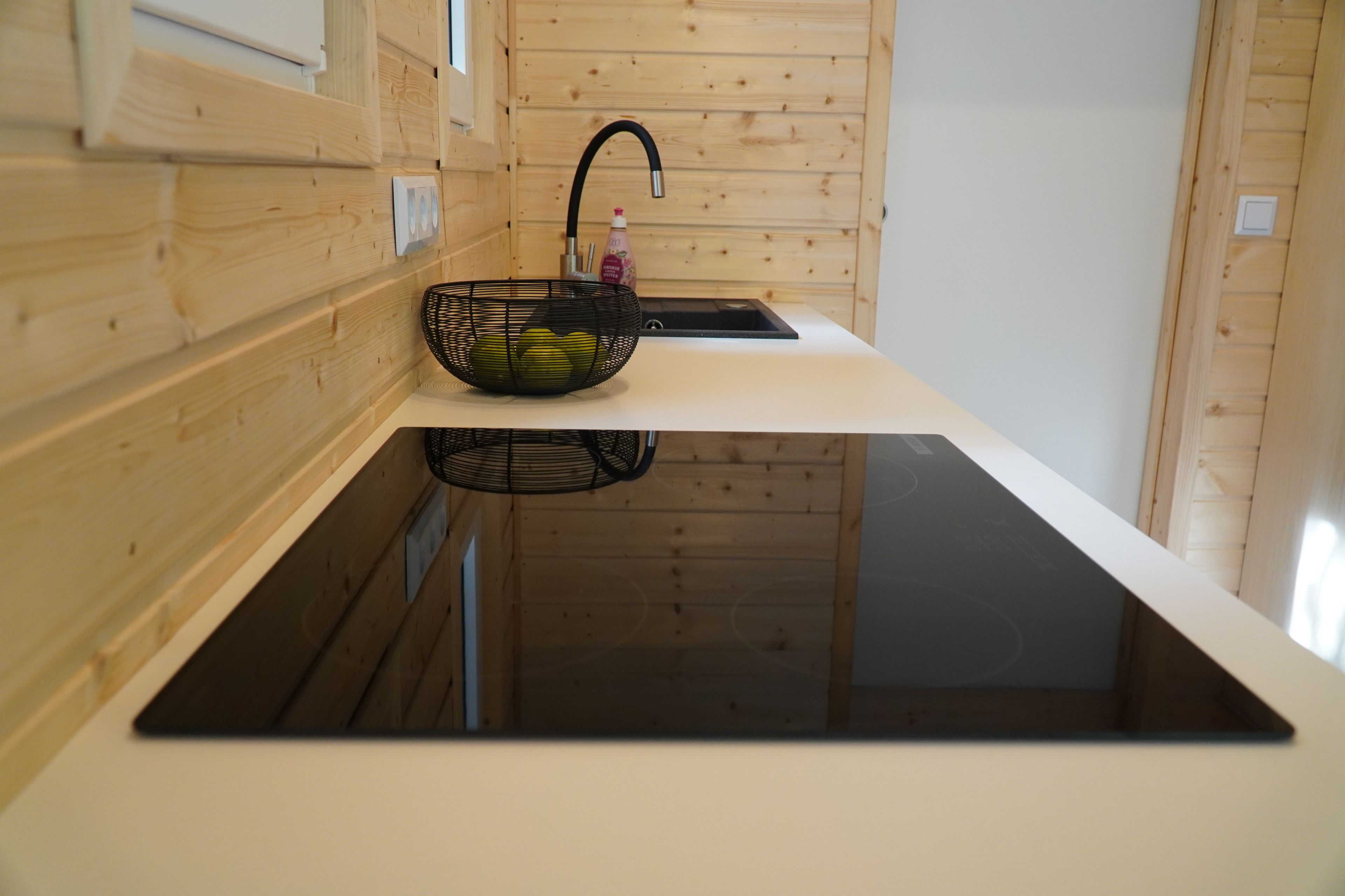 Eine moderne Küche mit Holzvertäfelung, einem schwarzen Spülbecken und einer schwarzen Arbeitsplatte.
