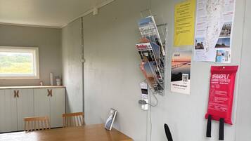 A room with a wooden table and chairs, a window with a view, a wall-mounted fire extinguisher, and various informational posters.