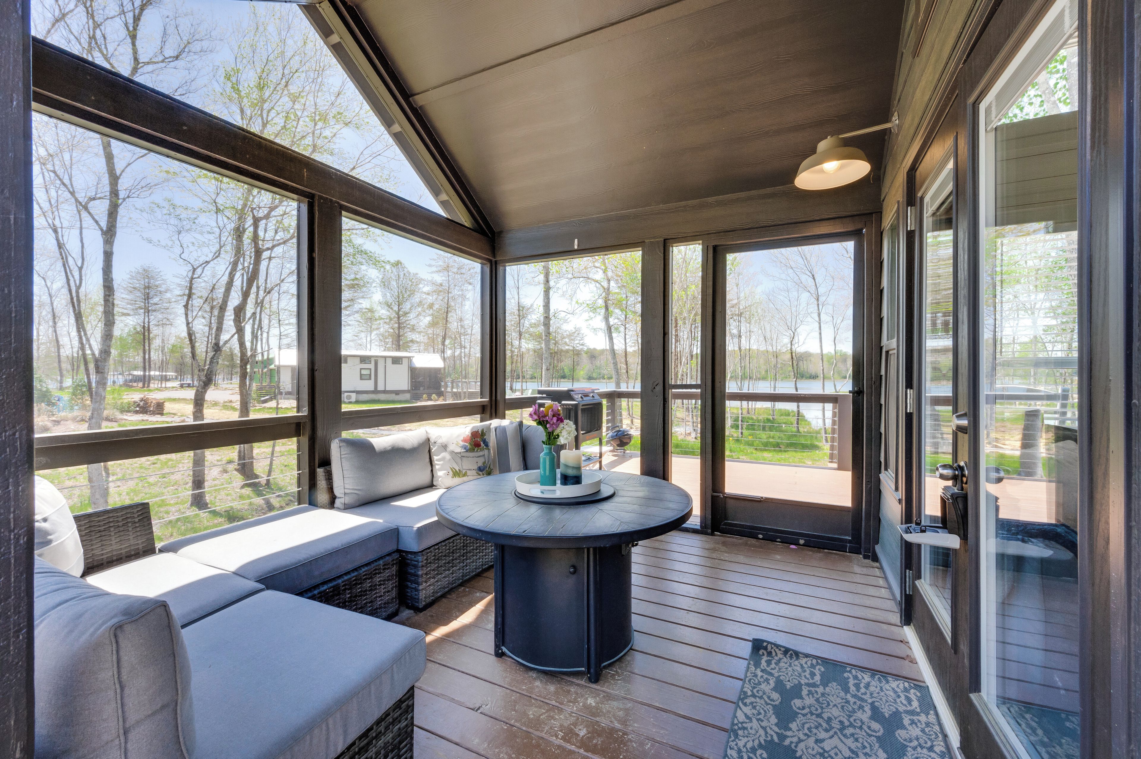 A covered outdoor seating area with a table and cushions, overlooking a natural landscape.