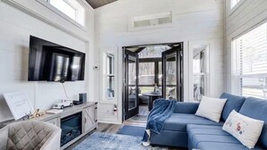 Una sala de estar moderna con una televisión de pantalla plana, un sofá azul, un sillón con reposabrazos y una mesa de centro.