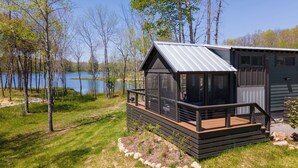 Una cabaña con balcón que da a un lago, rodeada de árboles.