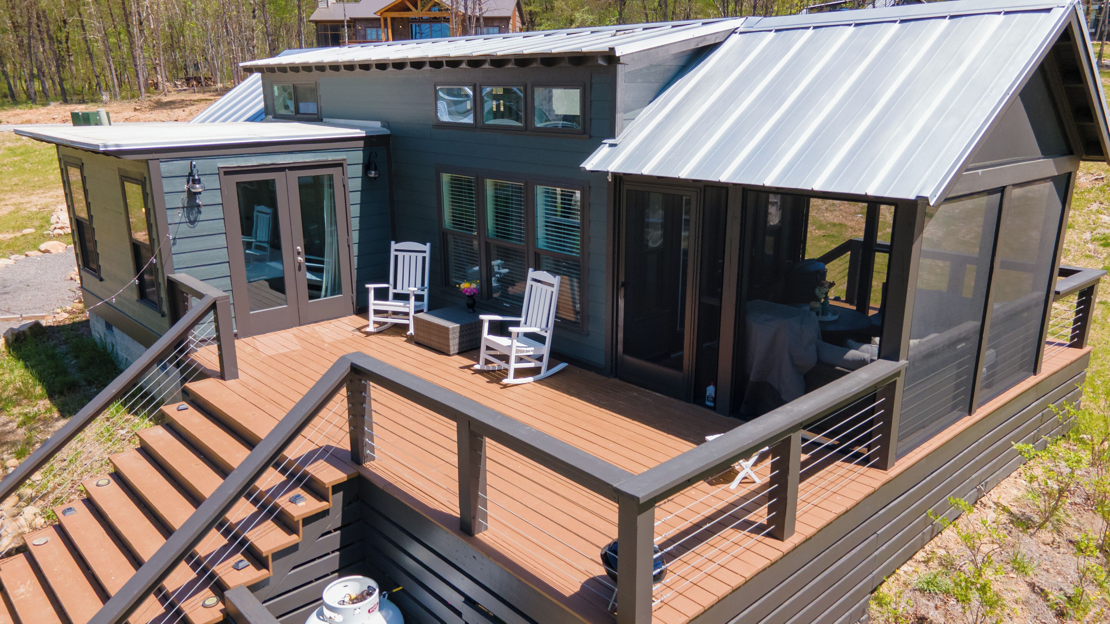 Eine moderne Holzhütte mit einer Terrasse, Sitzgelegenheiten im Freien und einem überdachten Bereich.