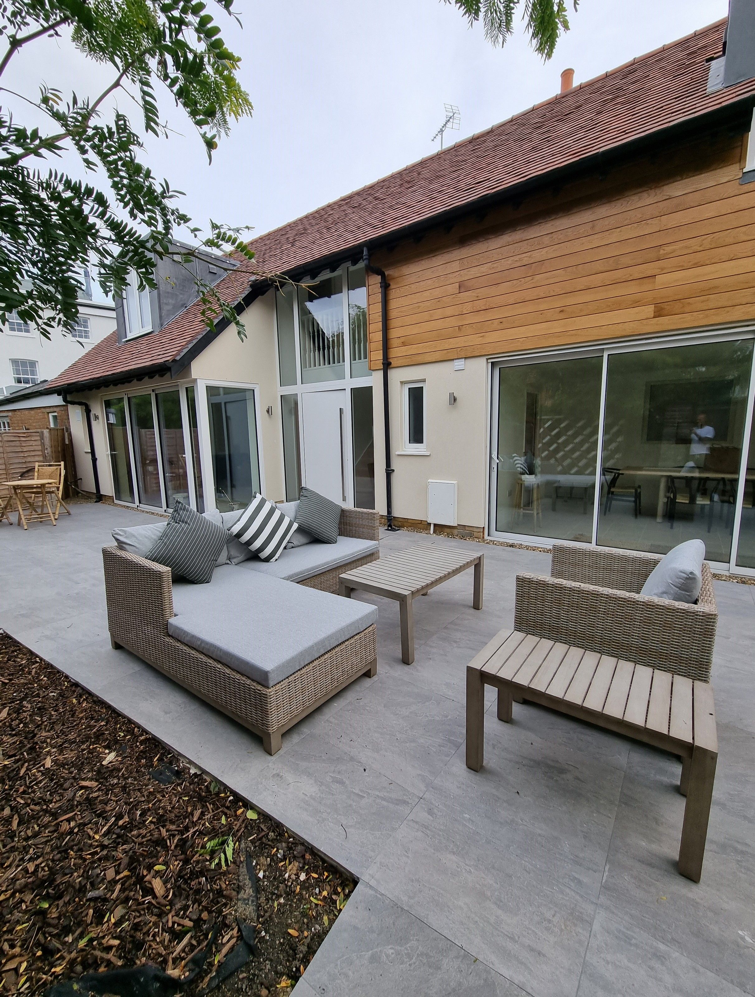A house with a patio area featuring outdoor furniture and a sliding glass door leading to an interior space.