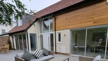 A house with a patio area featuring outdoor furniture and a sliding glass door leading to an interior space.
