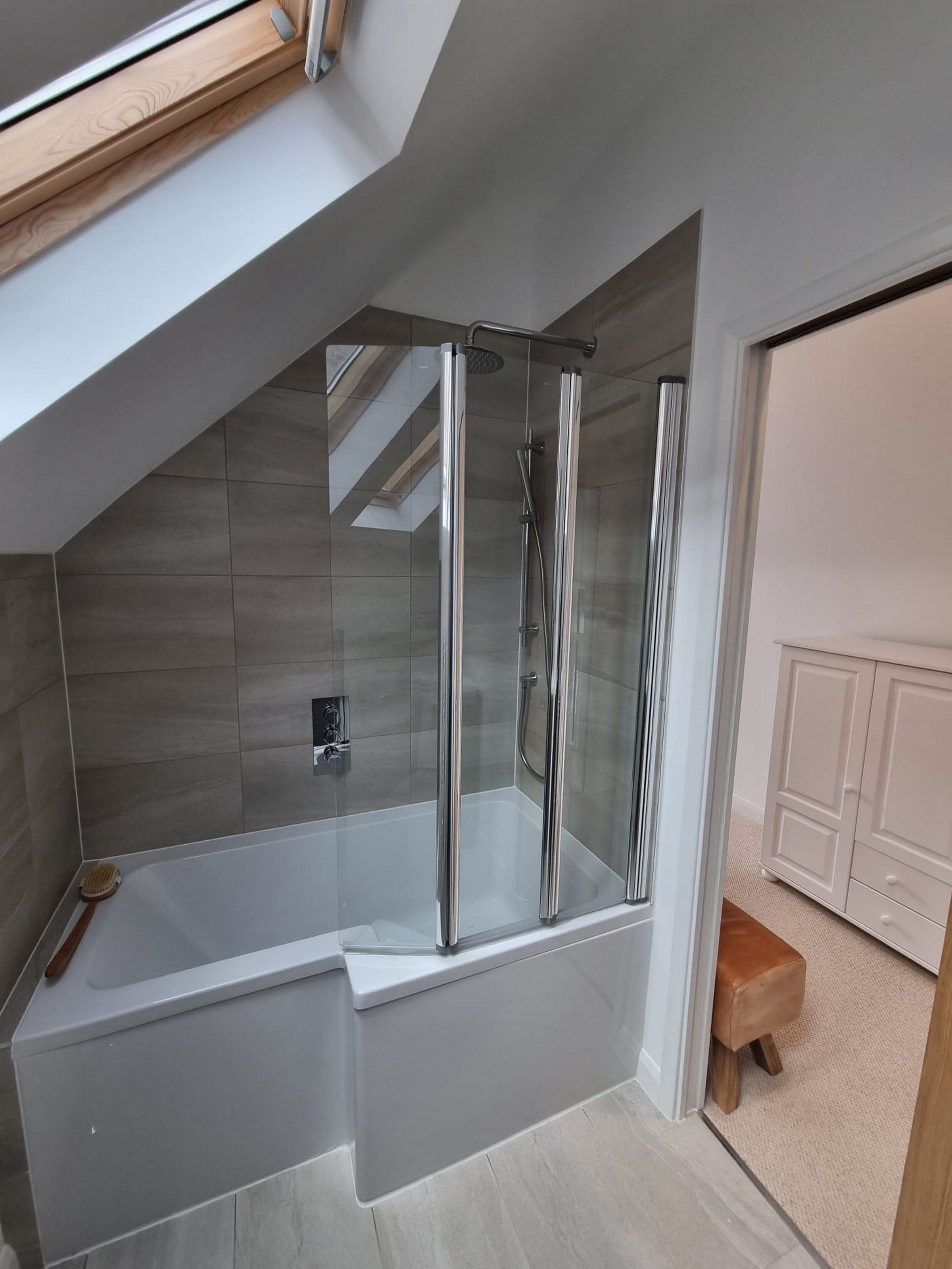 A modern bathroom with a glass-enclosed shower, a bathtub, and a skylight above.