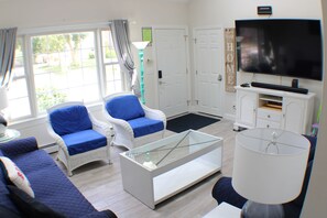 A living room with a sofa, two armchairs, a glass coffee table, a TV, and a lamp. - Bonnet Shores Getaway, 3BR, 10 min Walk to Private Beach (Narragansett)