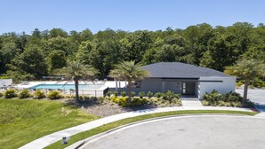 A modern building with a swimming pool, surrounded by lush greenery and palm trees.