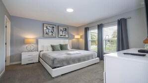 A modern bedroom with a bed, bedside tables, a desk, and a window with curtains.