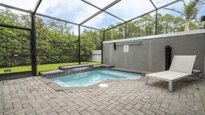 Una piscina interior con cerramiento de vidrio, una tumbona y un cartel que indica prohibido bañarse.