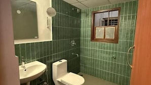 Casa de banho com lavatório, sanita e janela.