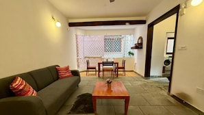Uma sala de estar com sofá, mesa de centro e área de jantar com cadeiras.