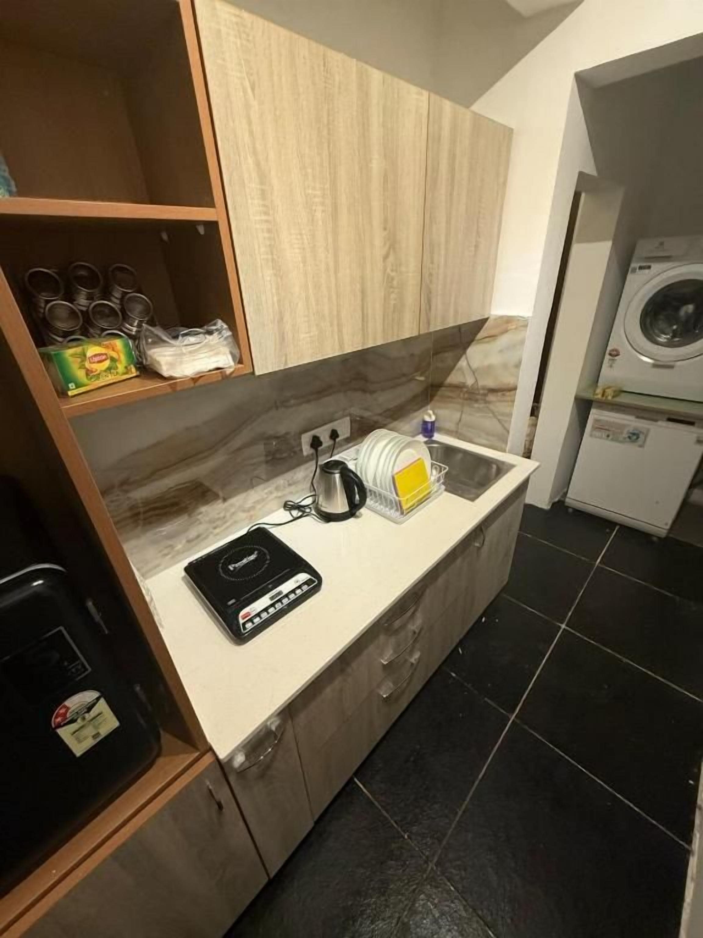 Una cocina funcional con mostrador, lavadora y estante con utensilios de cocina.