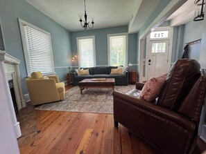 A living room with a fireplace, a sofa, a coffee table, and a leather armchair. - DriftAway - Historic 3 Bedroom Wilmington Retreat (Wilmington)