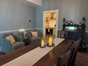 A living room with a sofa set, a dining table with candles, and a kitchen in the background. - DriftAway - Historic 3 Bedroom Wilmington Retreat (Wilmington)