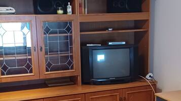 A bedroom with a bed, wooden cabinets, a television, and a window with decorative glass.
