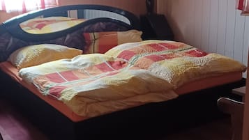 A bedroom with a bed, a chair, a lamp, and a window with curtains.