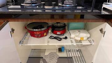 Cozinha com fogão, duas panelas vermelhas, eletrodoméstico branco e um recipiente azul.