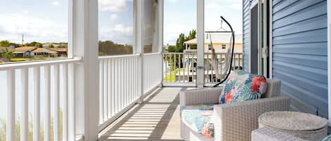 A covered porch with wicker furniture and a view of the neighborhood.