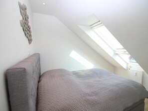 Ein Schlafzimmer mit schrägem Dach und einem Oberlicht.