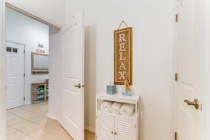 A hallway with a door labeled 'CDA,' a 'RELAX' sign, and a small table with towels and a tissue box.