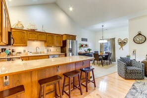 A spacious kitchen with wooden cabinets, a large island with stools, and a dining area with a table and chairs.