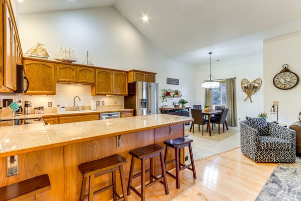 A spacious kitchen with wooden cabinets, a large island with stools, and a dining area with a table and chairs.