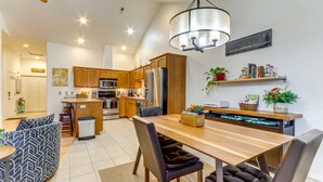 Una cocina moderna con armarios de madera, electrodomésticos de acero inoxidable y un comedor con mesa y sillas de madera.