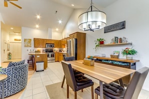 A modern kitchen with wooden cabinets, stainless steel appliances, and a dining area with a wooden table and chairs. - Charming Condo in the Heart of CDA, Walking Distance to Lake (Coeur d'Alene)