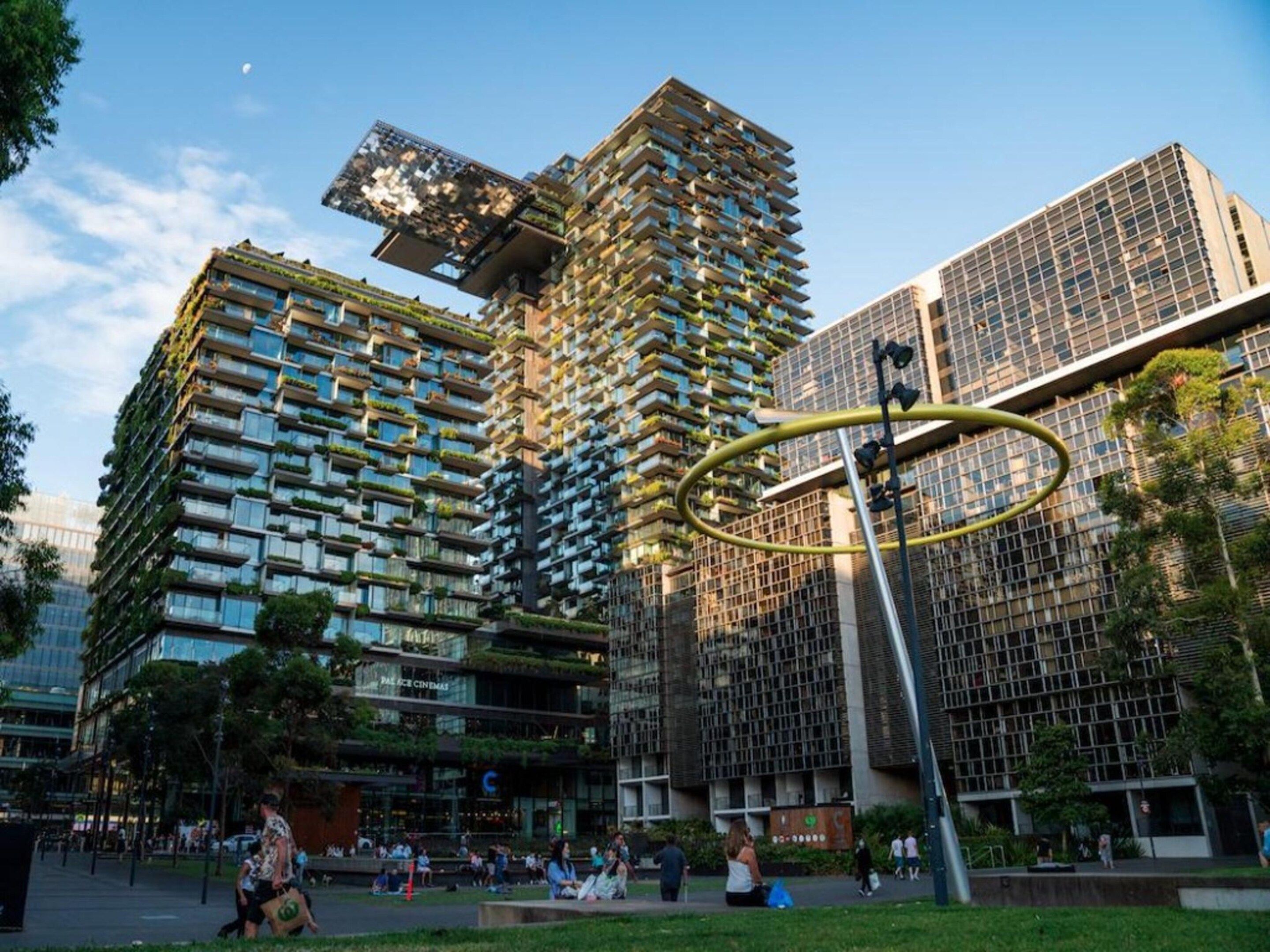 A modern urban building complex with multiple high-rise structures, some with balconies and greenery.