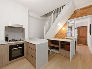 A modern kitchen with a built-in oven, a white countertop, and a wooden cabinet. - Stylish 2-bed House Near Sydney CBD (Sydney)