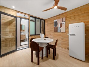 A modern kitchen with a white refrigerator, wooden walls, a round dining table with chairs, and a ceiling fan. - Stylish 2-bed House Near Sydney CBD (Sydney)