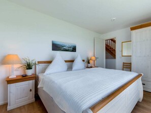 A bedroom with a bed, nightstands, a painting, a staircase, and a wardrobe. - Holiday Home With 2 Bedrooms (Kappeln)