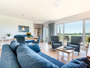 A modern living room with a large sofa, two armchairs, a coffee table, and a dining area with a blue tiled backsplash. - Holiday Home With 2 Bedrooms (Kappeln)