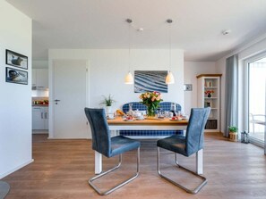 A modern dining area with two chairs, a table set with dishes, and a blue tiled backsplash. - Holiday Home With 2 Bedrooms (Kappeln)