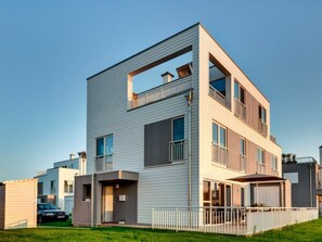 Ein modernes, mehrgeschossiges Wohngebäude mit flachem Dach, großen Fenstern und Balkonen.